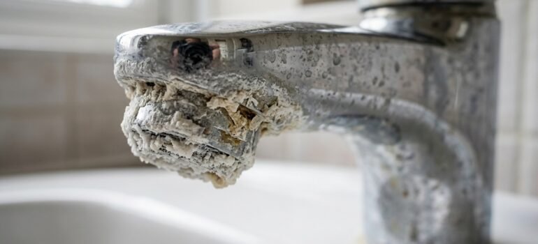 Heavy calcium and limescale buildup on a chrome bathroom faucet, illustrating hard water damage in Northern Utah homes.